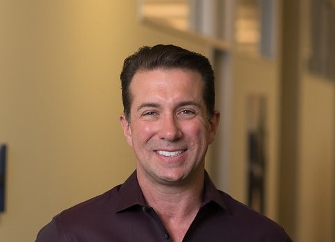 Brandon Frere smiling in a maroon collared shirt